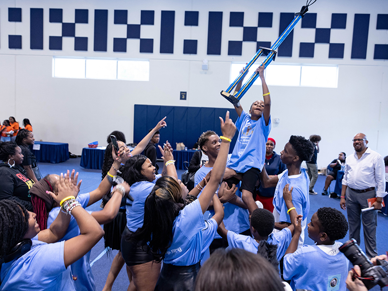 Children hoisting a trophy at the Flagway Math Tournament